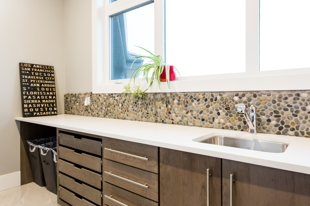 Photo of a large contemporary l-shaped separated utility room in Calgary with a submerged sink, flat-panel cabinets, engineered stone countertops, grey walls, ceramic flooring, a side by side washer and dryer, grey floors and dark wood cabinets.