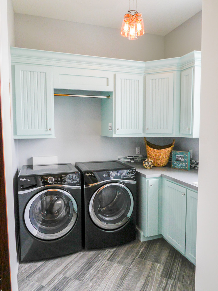 Foto de lavadero en L clásico renovado con puertas de armario azules, paredes grises, lavadora y secadora juntas y armarios con paneles empotrados