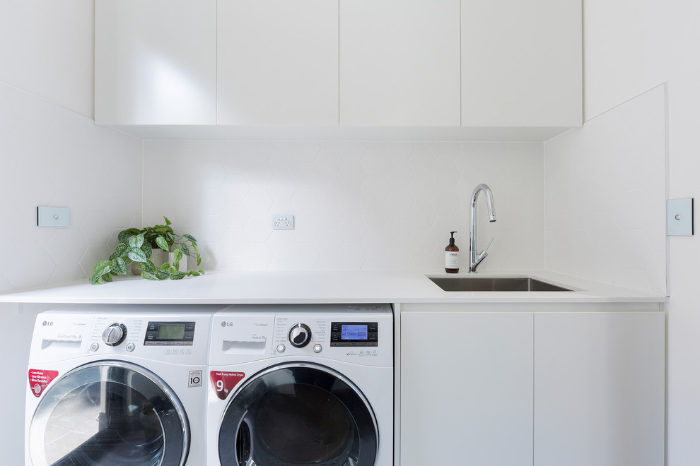 Esempio di una lavanderia contemporanea con lavello sottopiano, ante lisce, ante bianche, top in quarzo composito, pareti bianche, lavatrice e asciugatrice affiancate e top bianco