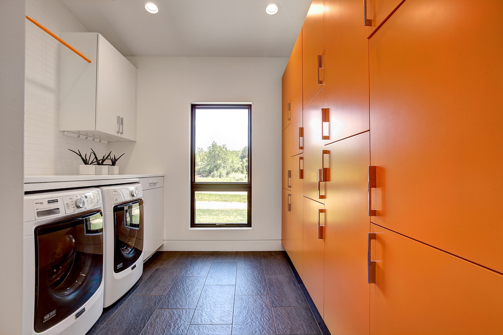 Foto di una sala lavanderia design di medie dimensioni con ante lisce, top in quarzo composito, pavimento in ardesia, lavatrice e asciugatrice affiancate, ante arancioni e pareti bianche