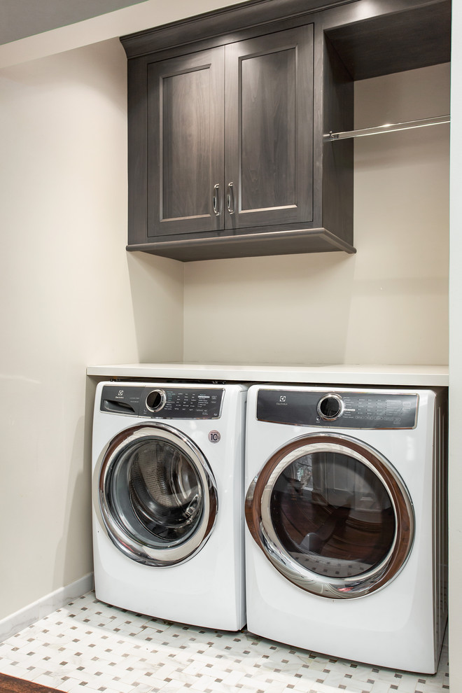 Example of a small trendy single-wall marble floor and multicolored floor dedicated laundry room design in Dallas with recessed-panel cabinets, gray cabinets, quartz countertops, beige walls, a side-by-side washer/dryer and white countertops