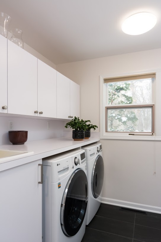 Immagine di una lavanderia multiuso minimalista di medie dimensioni con pareti bianche, lavello da incasso, ante bianche, top in laminato e lavatrice e asciugatrice affiancate