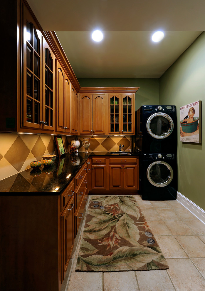 Inspiration for a mid-sized contemporary ceramic tile and beige floor laundry room remodel in DC Metro with a single-bowl sink, raised-panel cabinets, granite countertops, green walls, a stacked washer/dryer and medium tone wood cabinets