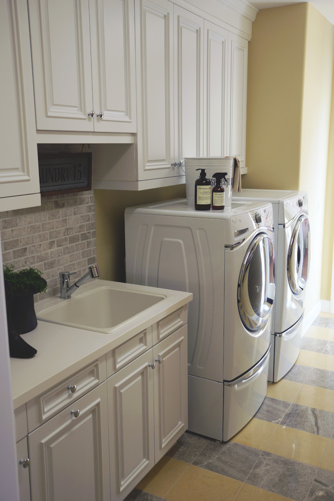 Example of a large tuscan single-wall dedicated laundry room design in San Diego with a drop-in sink, raised-panel cabinets, white cabinets, quartz countertops, beige walls and a side-by-side washer/dryer