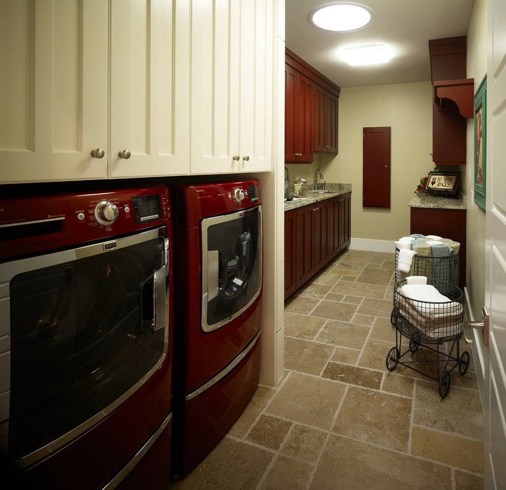 Bild på en mellanstor vintage parallell tvättstuga enbart för tvätt, med en undermonterad diskho, luckor med infälld panel, röda skåp, granitbänkskiva, beige väggar, klinkergolv i keramik och en tvättmaskin och torktumlare bredvid varandra
