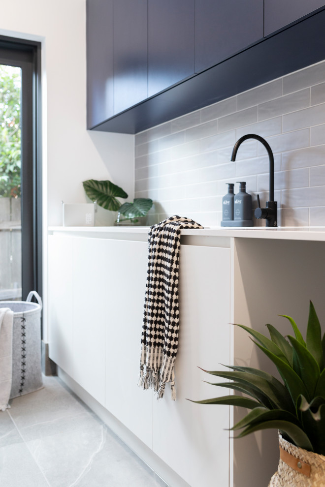 Design ideas for a medium sized modern single-wall separated utility room in Canberra - Queanbeyan with a submerged sink, engineered stone countertops, grey splashback, metro tiled splashback, white walls, porcelain flooring, a side by side washer and dryer, grey floors and white worktops.