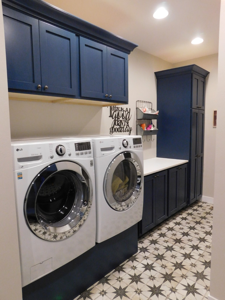 Ejemplo de lavadero multiusos y de galera retro con armarios con paneles lisos, puertas de armario azules, encimera de cuarzo compacto, paredes blancas, suelo de baldosas de porcelana y lavadora y secadora juntas