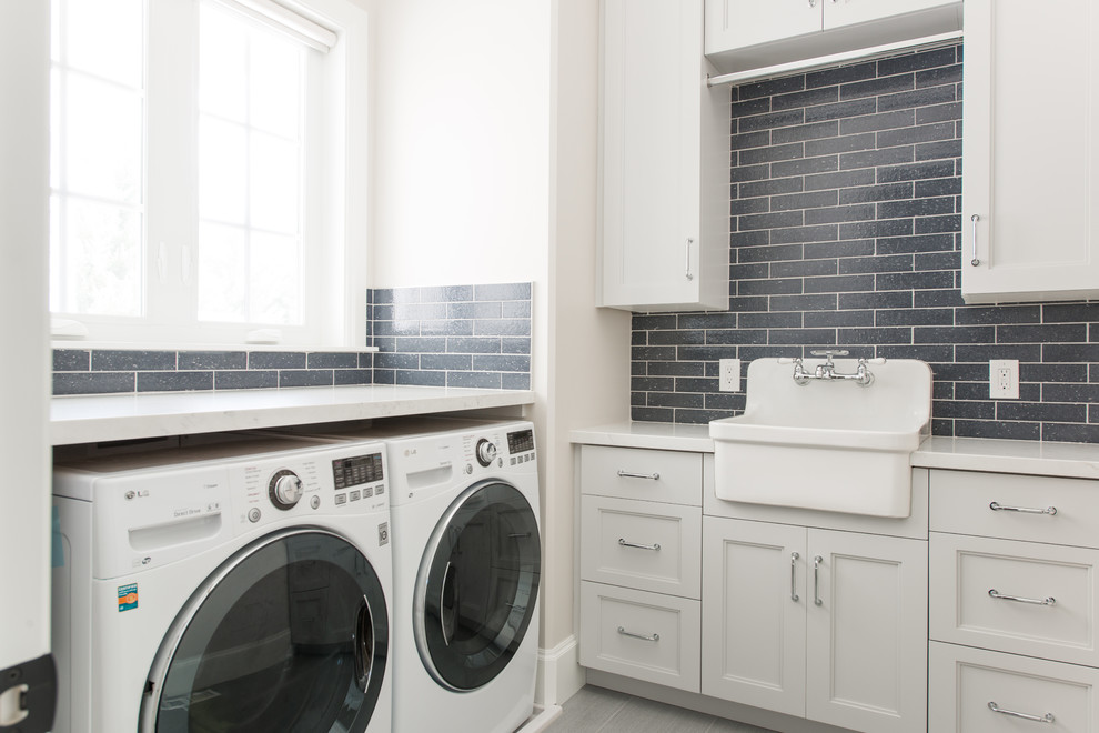 Idéer för att renovera en vintage vita l-formad vitt tvättstuga enbart för tvätt, med en rustik diskho, luckor med infälld panel, vita skåp, beige väggar, en tvättmaskin och torktumlare bredvid varandra och grått golv