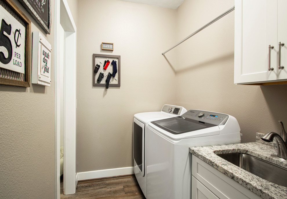 Inspiration för mellanstora klassiska linjära grått tvättstugor enbart för tvätt, med grå väggar, en undermonterad diskho, släta luckor, vita skåp, bänkskiva i kvartsit, vinylgolv, en tvättmaskin och torktumlare bredvid varandra och brunt golv