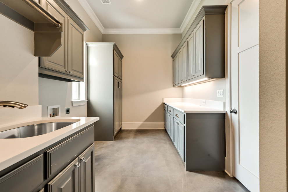 Photo of a large classic galley separated utility room in Dallas with a submerged sink, beige walls, concrete flooring and a side by side washer and dryer.