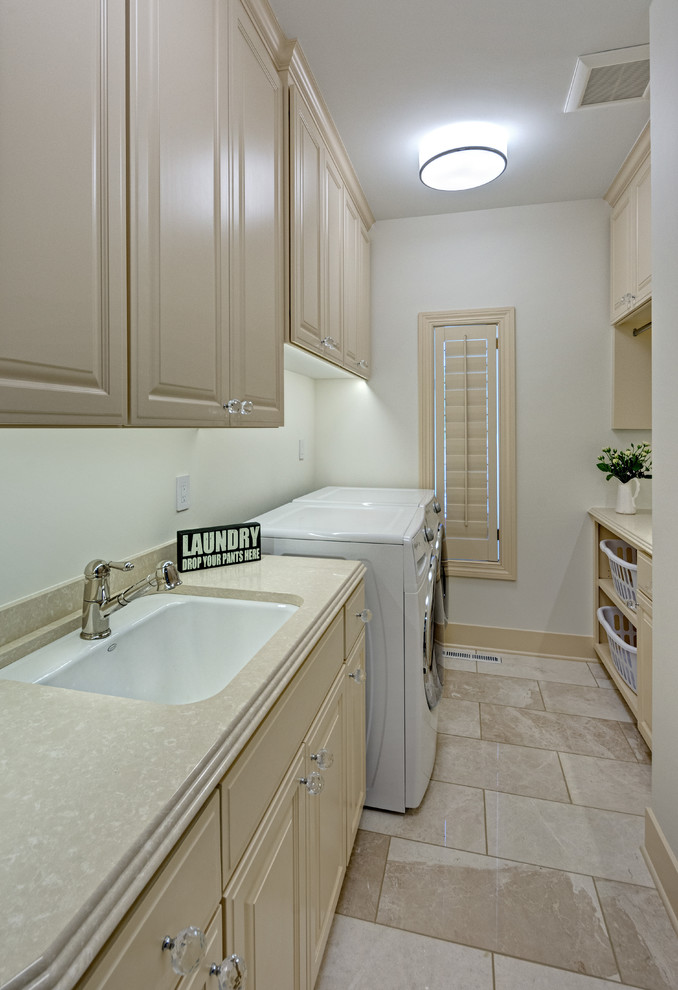 Dedicated laundry room - small traditional galley ceramic tile dedicated laundry room idea in Minneapolis with a drop-in sink, raised-panel cabinets, beige cabinets, granite countertops, white walls and a side-by-side washer/dryer