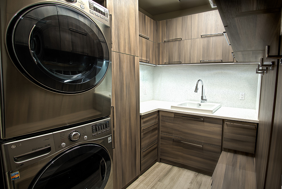 Foto di una sala lavanderia minimalista di medie dimensioni con ante lisce, ante in legno bruno, lavatrice e asciugatrice a colonna, lavello da incasso, pavimento in gres porcellanato e pavimento beige