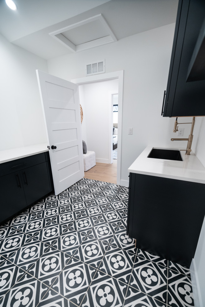 Medium sized modern galley separated utility room in Denver with a submerged sink, flat-panel cabinets, black cabinets, quartz worktops, ceramic flooring, a side by side washer and dryer, black floors and white worktops.