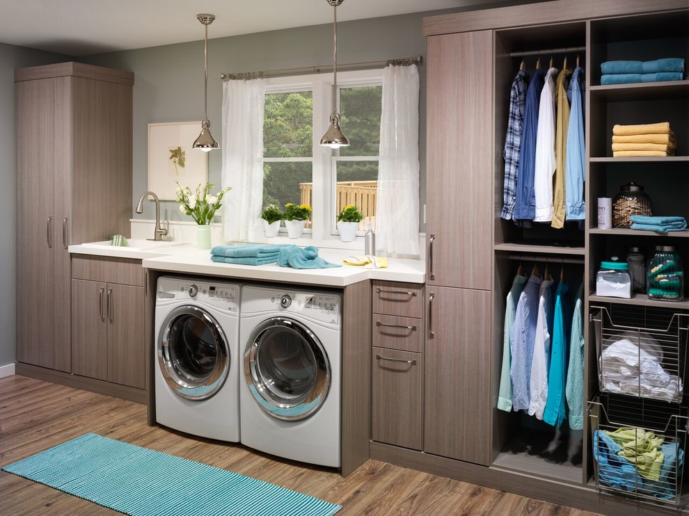 Immagine di una lavanderia contemporanea con lavello da incasso, ante lisce, pareti grigie, pavimento in legno massello medio, lavatrice e asciugatrice affiancate, top bianco e ante grigie