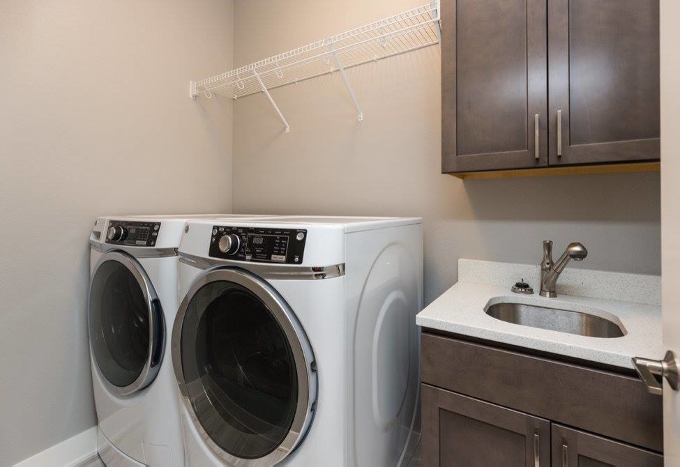 Inspiration for a mid-sized contemporary single-wall dedicated laundry room remodel in Other with an undermount sink, shaker cabinets, dark wood cabinets, quartz countertops, beige walls, a side-by-side washer/dryer and white countertops