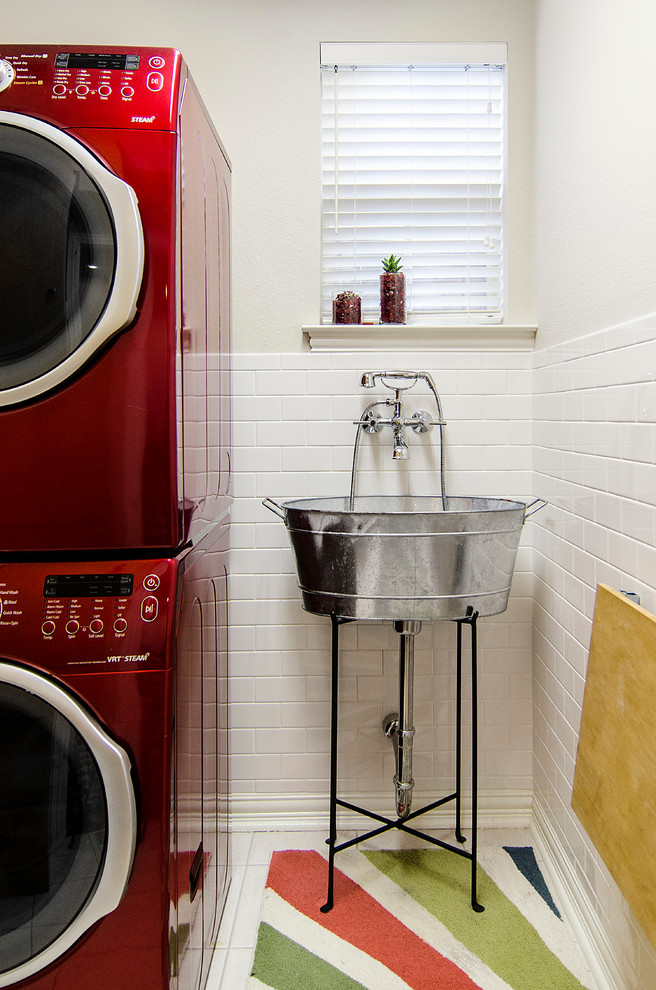 Imagen de lavadero clásico con pila para lavar, lavadora y secadora apiladas, paredes blancas, suelo de baldosas de cerámica y suelo blanco