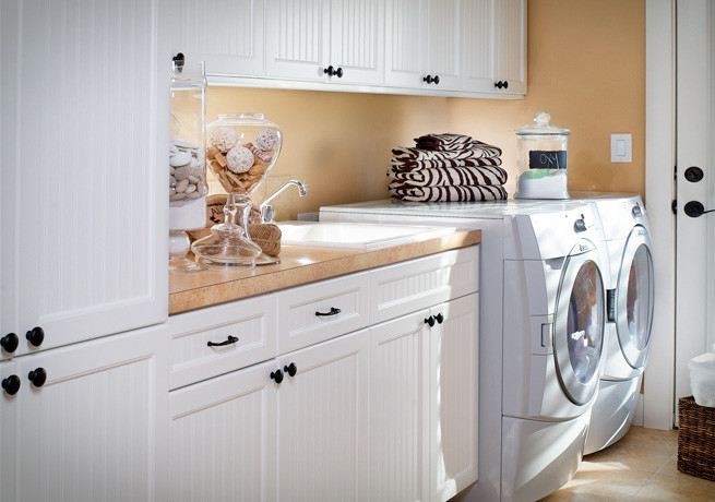 This is an example of a modern single-wall utility room in Seattle with a built-in sink, white cabinets, laminate countertops, a side by side washer and dryer and recessed-panel cabinets.