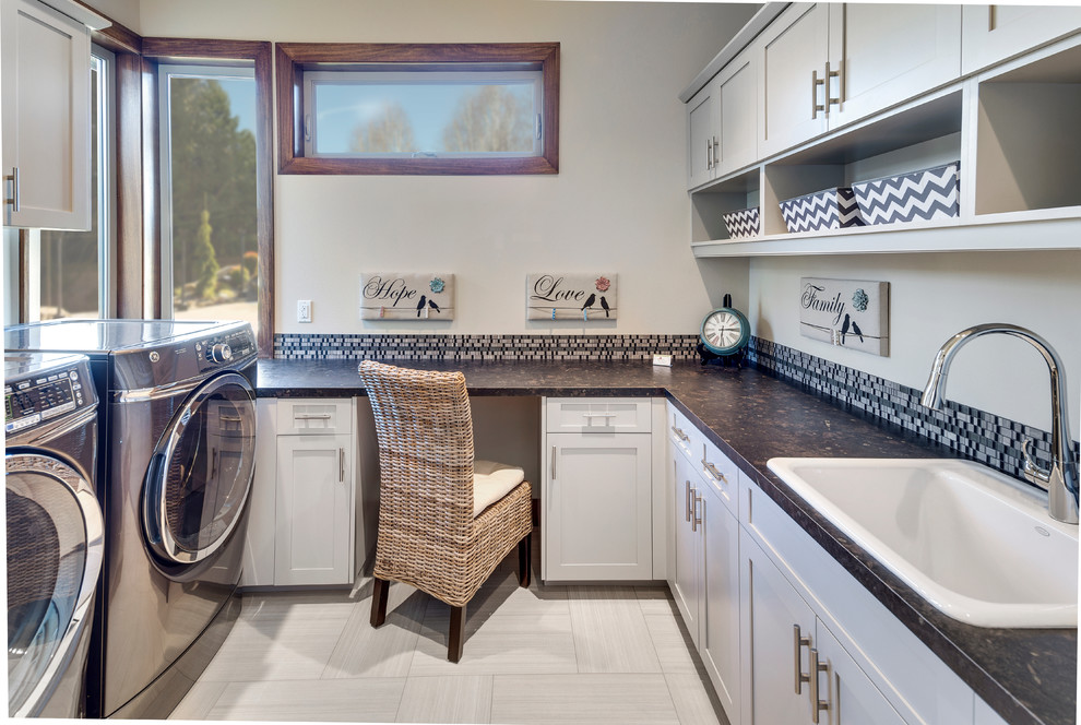 Foto di una sala lavanderia tradizionale di medie dimensioni con lavello da incasso, ante in stile shaker, ante bianche, pareti bianche, pavimento in gres porcellanato, lavatrice e asciugatrice affiancate e pavimento grigio