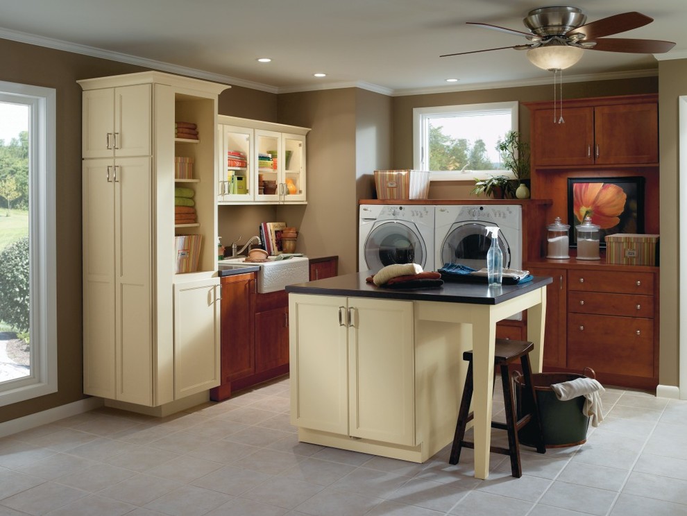 Inspiration for a large traditional l-shaped utility room in Other with shaker cabinets, medium wood cabinets, a side by side washer and dryer, a belfast sink, brown walls and ceramic flooring.