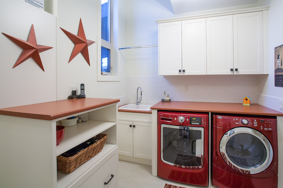 バンクーバーにあるトラディショナルスタイルのおしゃれなランドリールーム (ドロップインシンク、左右配置の洗濯機・乾燥機、赤いキッチンカウンター) の写真