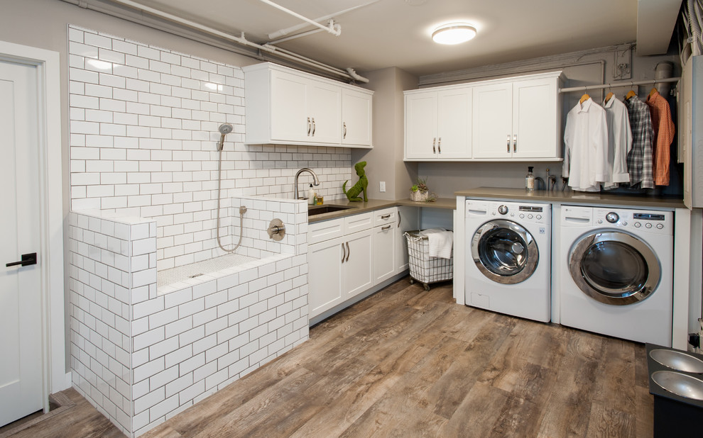 Cette image montre une buanderie traditionnelle en L multi-usage avec un évier encastré, un placard à porte shaker, des portes de placard blanches, un plan de travail en quartz modifié, un mur gris, un sol en vinyl et des machines côte à côte.