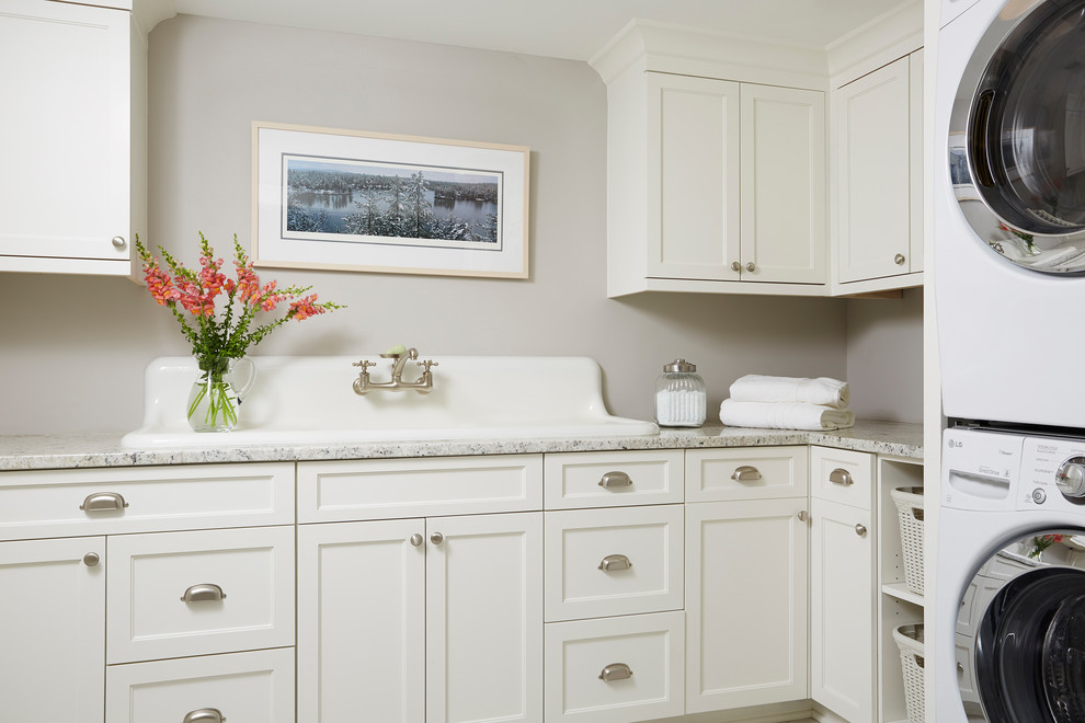 Foto de cuarto de lavado en L clásico con fregadero encastrado, armarios estilo shaker, puertas de armario blancas, paredes grises y lavadora y secadora apiladas