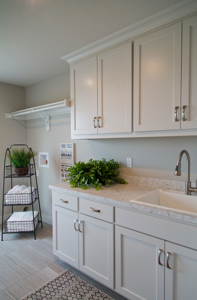 Inspiration for a mid-sized modern galley ceramic tile and multicolored floor dedicated laundry room remodel in Kansas City with a drop-in sink, shaker cabinets, white cabinets, marble countertops and gray walls