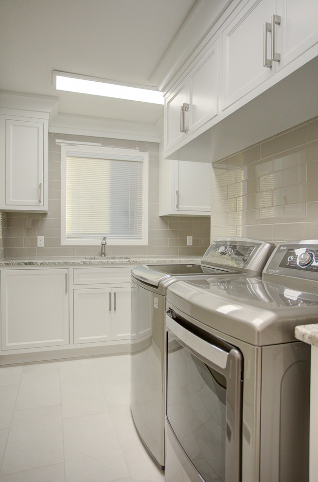 Photo of a large classic l-shaped utility room in Calgary with a submerged sink, recessed-panel cabinets, white cabinets, granite worktops, beige walls, ceramic flooring, a side by side washer and dryer, grey floors and multicoloured worktops.