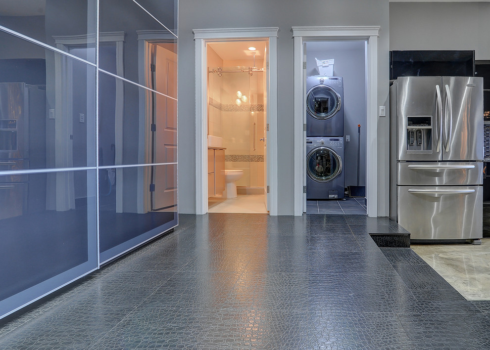 Ispirazione per un piccolo ripostiglio-lavanderia minimal con pareti grigie, pavimento in vinile, lavatrice e asciugatrice a colonna e pavimento grigio