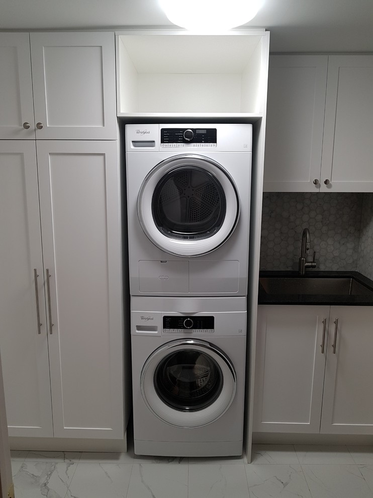 Inspiration for a large classic single-wall separated utility room in Toronto with a submerged sink, shaker cabinets, white cabinets, engineered stone countertops, marble flooring, a stacked washer and dryer and white floors.