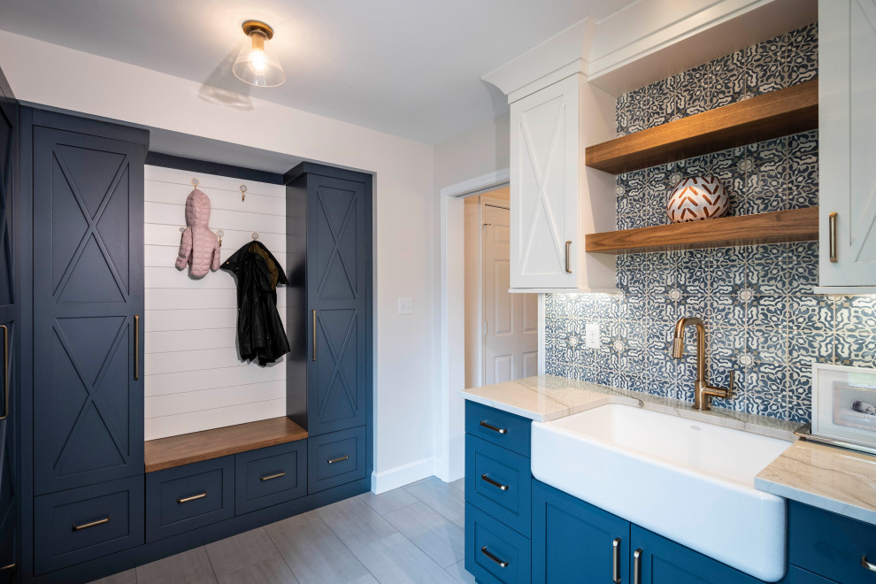 Utility room - large transitional porcelain tile and gray floor utility room idea in Indianapolis with a farmhouse sink, shaker cabinets, blue cabinets, quartz countertops, white walls, a side-by-side washer/dryer and white countertops