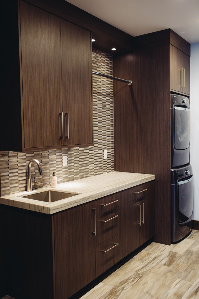 Photo of a medium sized traditional l-shaped separated utility room in Salt Lake City with a submerged sink, dark wood cabinets, a stacked washer and dryer, flat-panel cabinets, marble worktops, multi-coloured walls and dark hardwood flooring.