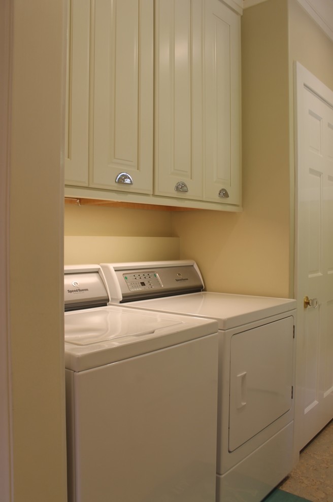 ロサンゼルスにあるお手頃価格の中くらいなトランジショナルスタイルのおしゃれな洗濯室 (レイズドパネル扉のキャビネット、白いキャビネット、クオーツストーンカウンター、白いキッチンパネル、セラミックタイルのキッチンパネル、コルクフローリング、白い床、ll型、ベージュの壁、左右配置の洗濯機・乾燥機) の写真