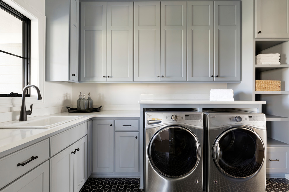 Large beach style l-shaped separated utility room in Minneapolis with a built-in sink, grey cabinets, engineered stone countertops, white walls, ceramic flooring, a side by side washer and dryer, black floors, white worktops and shaker cabinets.