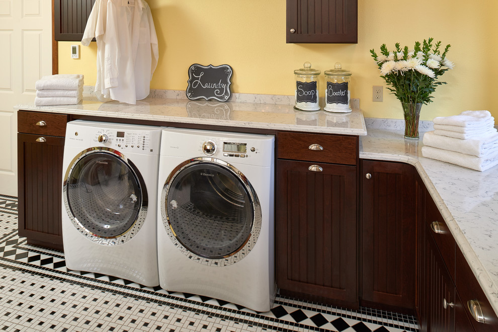 Exempel på en mycket stor klassisk tvättstuga enbart för tvätt, med skåp i shakerstil, skåp i mörkt trä, bänkskiva i kvarts, gula väggar, klinkergolv i porslin och en tvättmaskin och torktumlare bredvid varandra