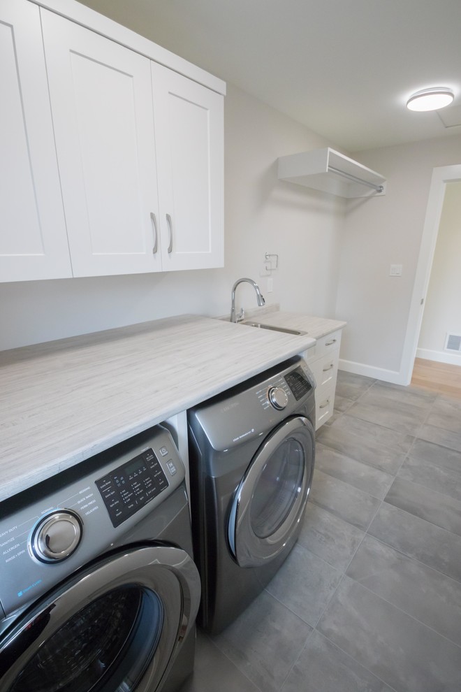 Medium sized classic single-wall separated utility room in Vancouver with an utility sink, recessed-panel cabinets, white cabinets, laminate countertops, grey walls, porcelain flooring, a side by side washer and dryer, grey floors and multicoloured worktops.