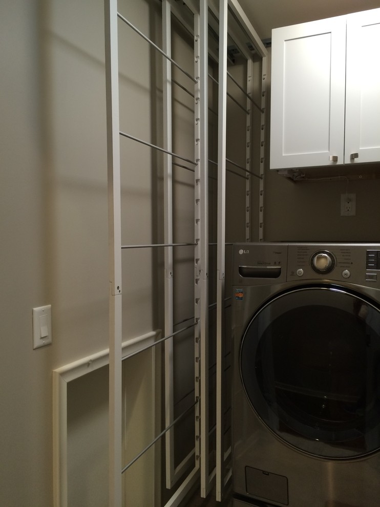 Kleiner, Einzeiliger Moderner Hauswirtschaftsraum mit weißen Schränken, grauer Wandfarbe und Waschmaschine und Trockner nebeneinander in Minneapolis