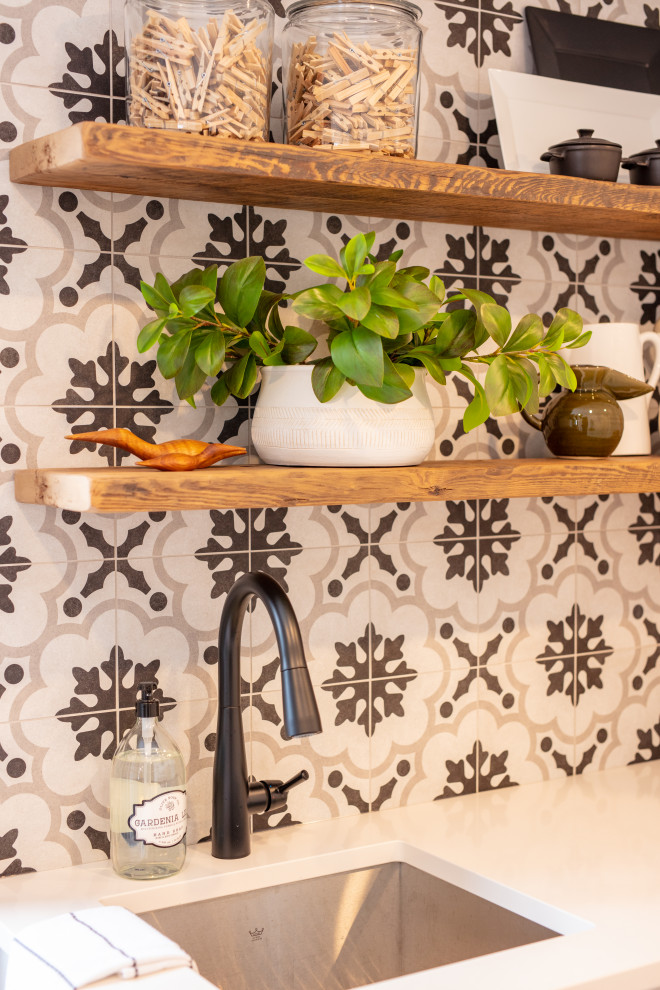 Example of a small classic single-wall porcelain tile and gray floor dedicated laundry room design in Ottawa with a single-bowl sink, shaker cabinets, white cabinets, quartz countertops, multicolored backsplash, porcelain backsplash, multicolored walls, a stacked washer/dryer and white countertops