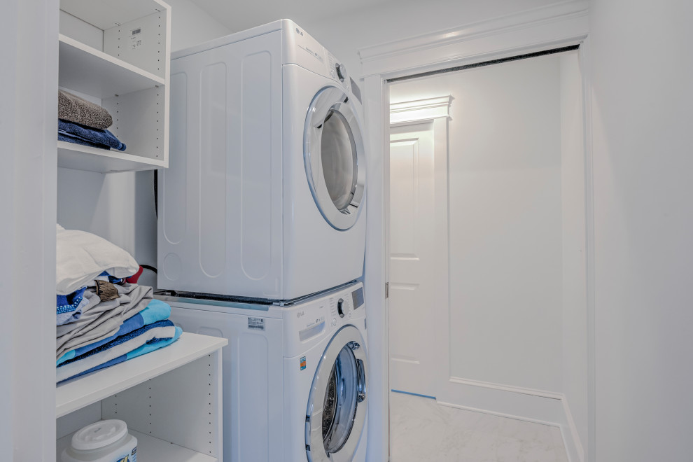 Einzeilige, Mittelgroße Maritime Waschküche mit offenen Schränken, weißen Schränken, weißer Wandfarbe und Waschmaschine und Trockner gestapelt in Sonstige