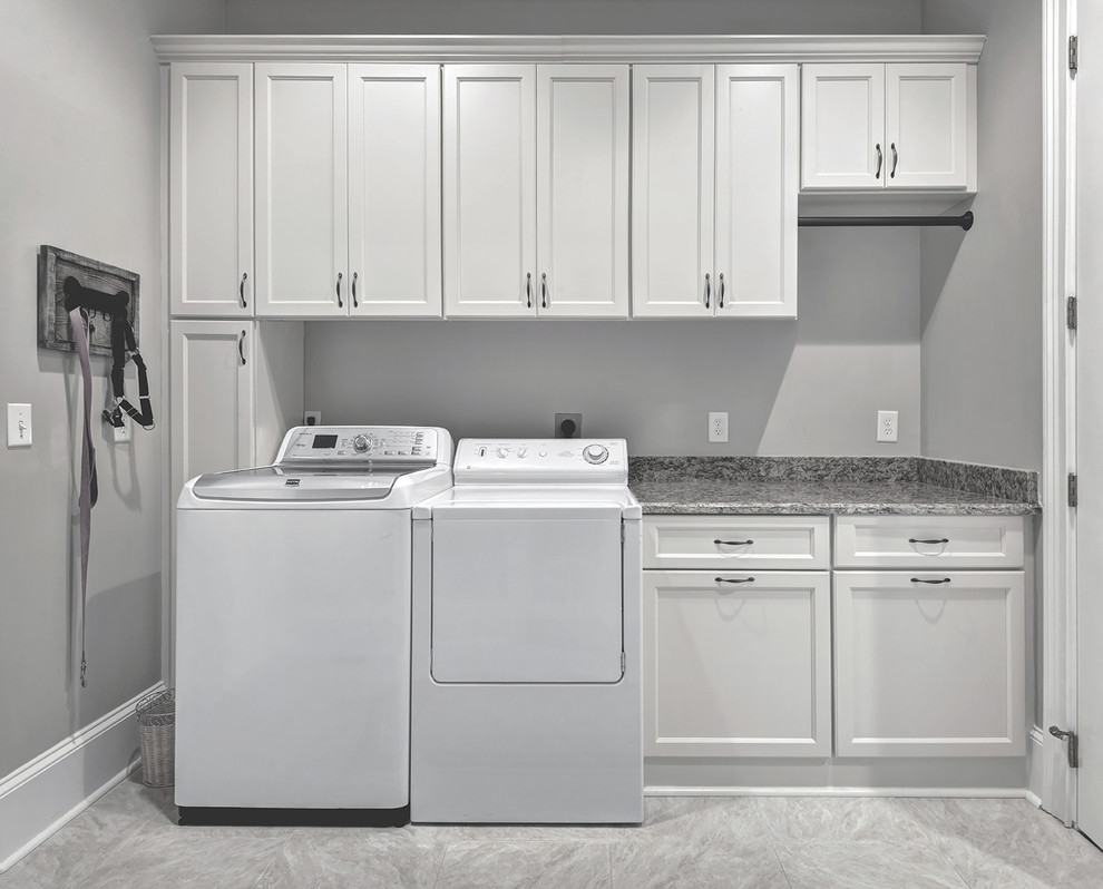 Einzeilige, Mittelgroße Moderne Waschküche mit flächenbündigen Schrankfronten, weißen Schränken, Granit-Arbeitsplatte, grauer Wandfarbe, Porzellan-Bodenfliesen und Waschmaschine und Trockner nebeneinander in Charleston