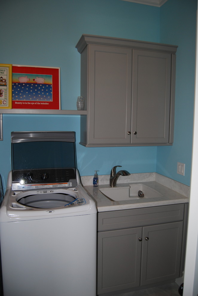 シンシナティにあるお手頃価格の中くらいなコンテンポラリースタイルのおしゃれな洗濯室 (スロップシンク、落し込みパネル扉のキャビネット、グレーのキャビネット、青い壁、左右配置の洗濯機・乾燥機) の写真