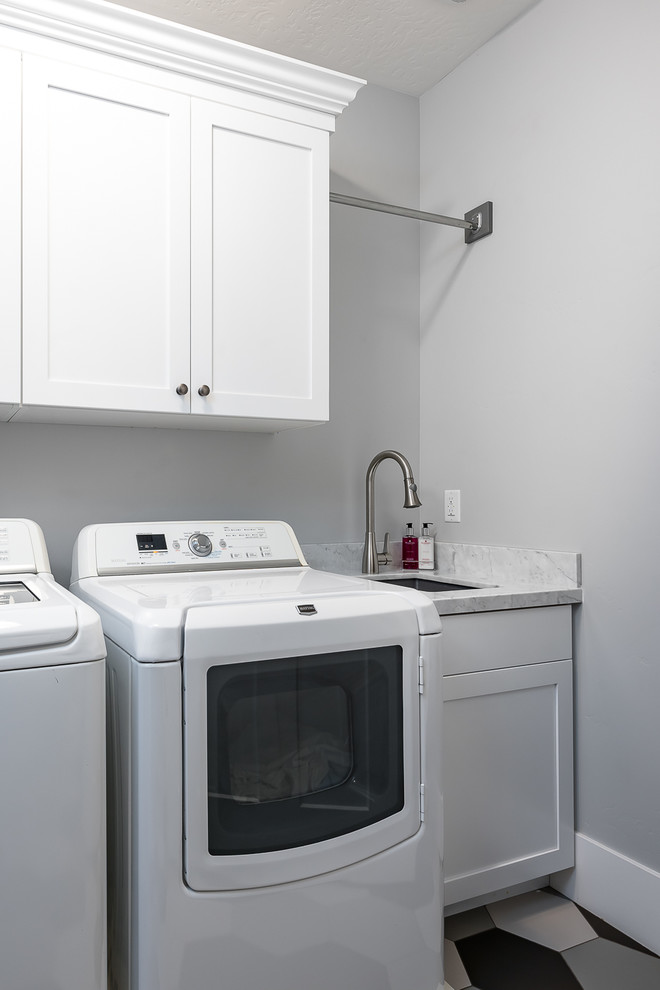 Idéer för mellanstora vintage linjära tvättstugor enbart för tvätt, med en undermonterad diskho, skåp i shakerstil, vita skåp, marmorbänkskiva, grå väggar, klinkergolv i porslin, en tvättmaskin och torktumlare bredvid varandra och flerfärgat golv