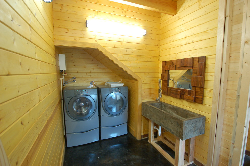 Foto på en mellanstor vintage linjär tvättstuga enbart för tvätt, med betonggolv, en tvättmaskin och torktumlare bredvid varandra och svart golv
