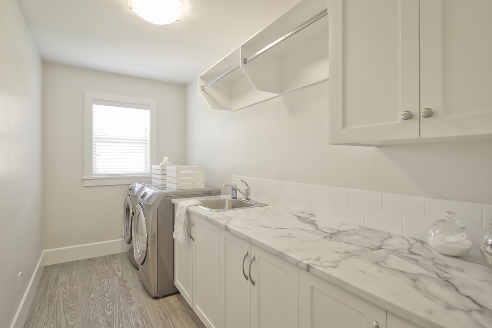 Design ideas for a medium sized contemporary single-wall separated utility room in Vancouver with a single-bowl sink, shaker cabinets, white cabinets, laminate countertops, white walls, vinyl flooring and a side by side washer and dryer.