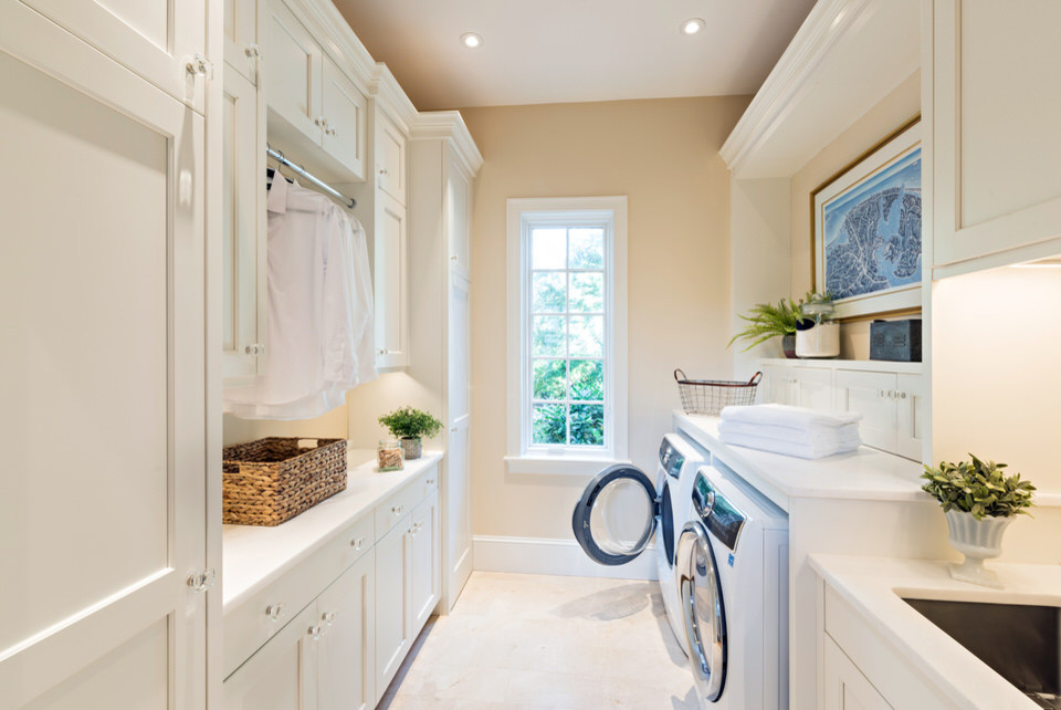 Immagine di una sala lavanderia chic di medie dimensioni con lavello a vasca singola, ante con riquadro incassato, ante bianche, top in quarzo composito, pareti beige, lavatrice e asciugatrice affiancate, pavimento beige e top bianco