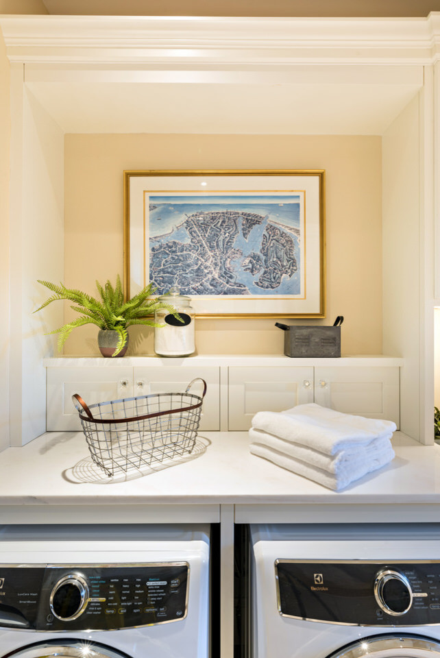 Bild på en mellanstor vintage vita parallell vitt tvättstuga enbart för tvätt, med luckor med infälld panel, vita skåp, bänkskiva i kvarts, beige väggar, en tvättmaskin och torktumlare bredvid varandra och beiget golv