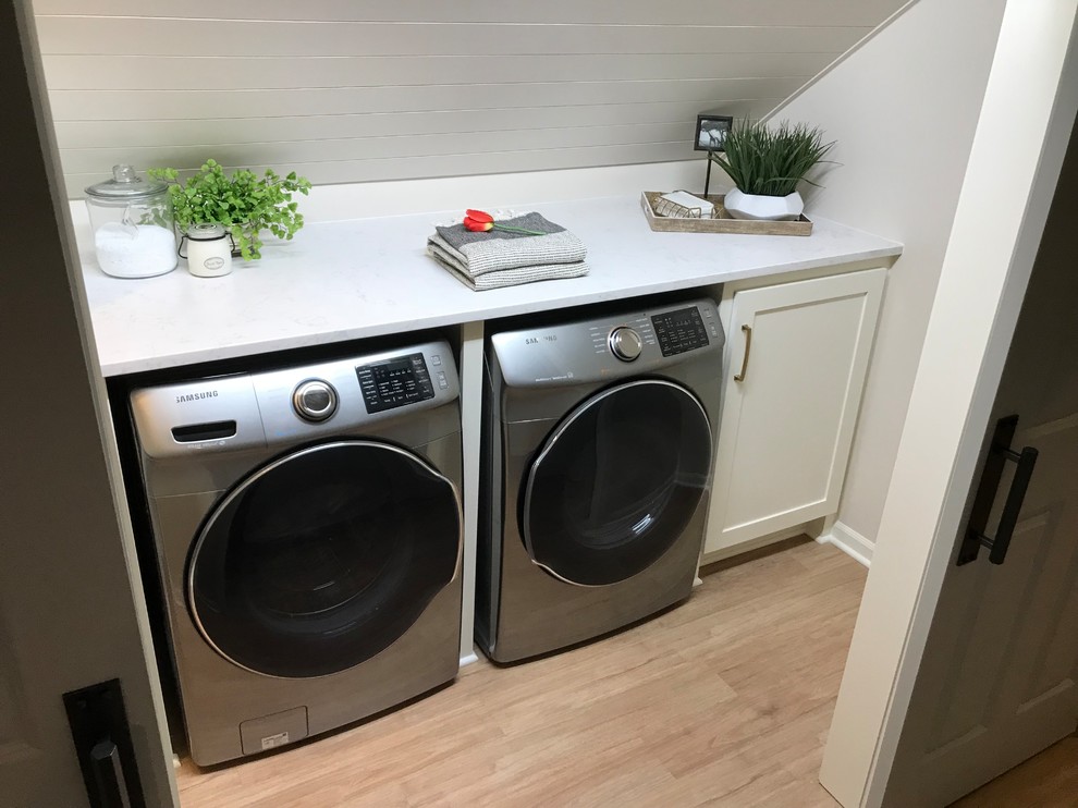 Exempel på en stor klassisk parallell tvättstuga enbart för tvätt, med skåp i shakerstil, vita skåp, bänkskiva i kvarts, vita väggar, vinylgolv, en tvättmaskin och torktumlare bredvid varandra och brunt golv