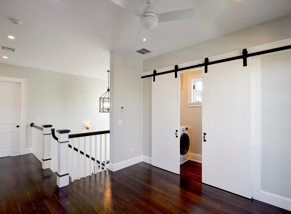 Diseño de lavadero lineal costero con paredes grises, suelo de madera oscura y puertas de armario blancas