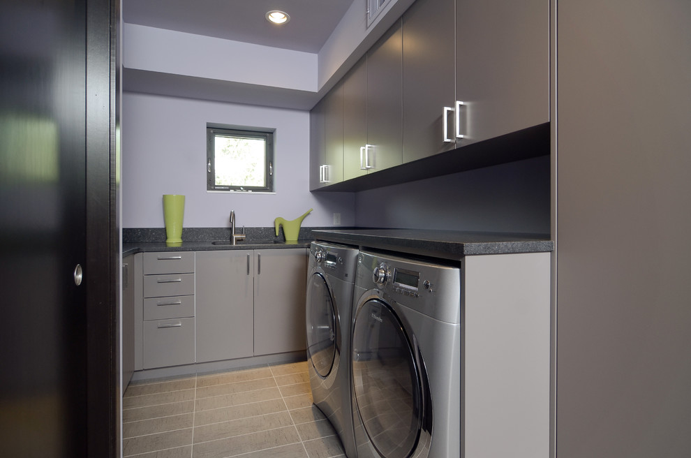 Bild på en funkis tvättstuga, med grå skåp och grått golv