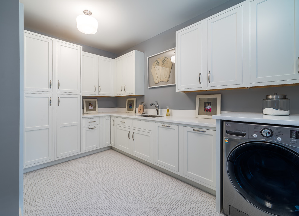 Imagen de cuarto de lavado en L tradicional renovado grande con fregadero de un seno, armarios con paneles empotrados, puertas de armario blancas y lavadora y secadora juntas
